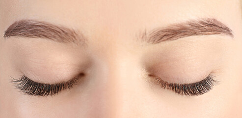 Young woman with beautiful eyelashes after extension procedure, closeup. Banner design
