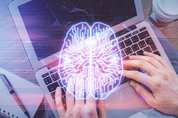 Double exposure of man's hands typing over computer keyboard and brain hologram drawing. Top view....