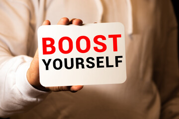 BOOST YOURSELF, message on the card shown by a man