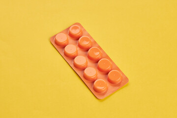 medical wellness concept. orange pills on a yellow background. copy space. minimal.