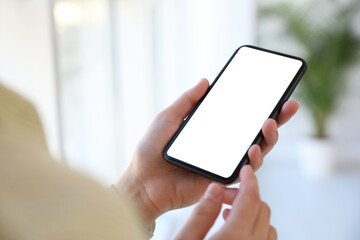 Woman holding mobile phone with empty screen indoors, closeup