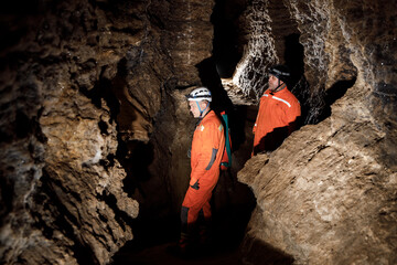 Two men, strong physique, explore the cave. Men dressed in special clothes to pass through the cave...