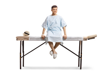 Young male patient in a hospital gown sitting on a medical bed
