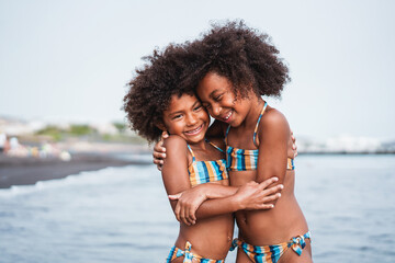 Black sister twins having fun on the beach during summer time - Little female kids laughing and...