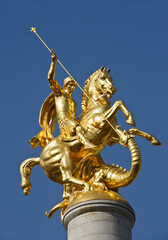 Fototapeta na wymiar Gold sculpture of St. George slaying a dragon atop a column in Freedom Square, Tbilisi, Georgia
