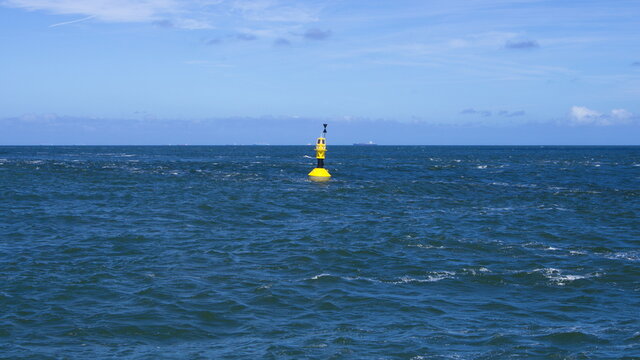 Gelbe Boje in rauer See mit Horizontlinie