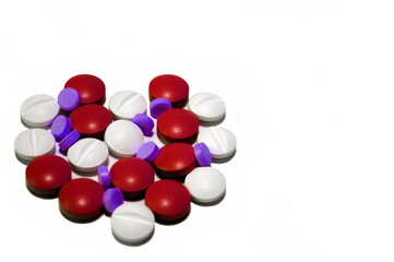 Medications, tablets of three colors (white, red and purple) lie on a white surface and laid out in the shape of a heart. Do not be sick - be healthy