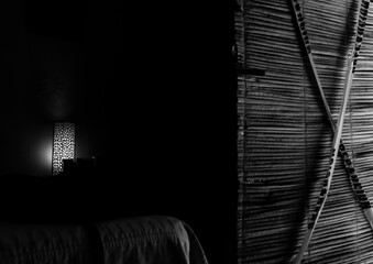 Abstract photo of light and shadow contrast of the texture of a rustic house and a lamp inside