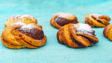 Some sweet cinnamon buns on the blurred turquoise background. Danish pastry. Sweet pastry for breakfast or snack.