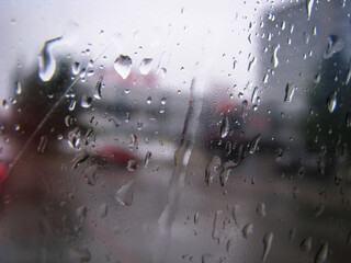 Drops on glass overlooking the street. Car window and the road behind it. Urban theme stock photo for design