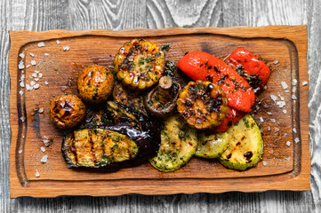 Various tasty grilled vegetables and mushrooms on rustic background