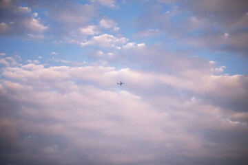 plane against the sky around a lot of beautiful clouds with pink light background