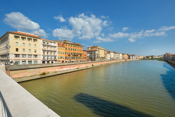 Fototapeta premium Colorful buildings line the banks of the Arno River in the Tuscan city of Pisa, Italy.