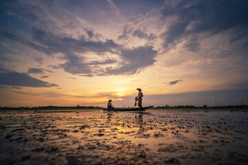 life of Asia two fisherman Silhouette using nets to catching fish at the lake in the sunset.