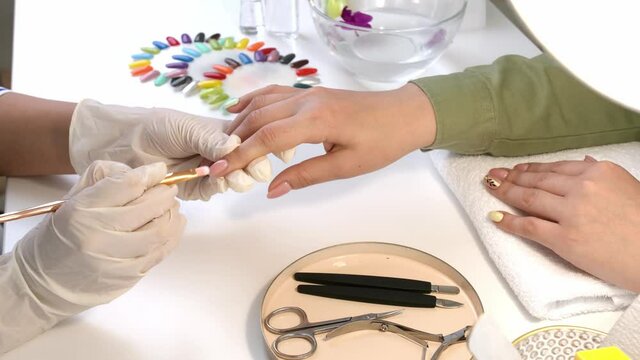 Manicure master working with female client in beauty salon, closeup