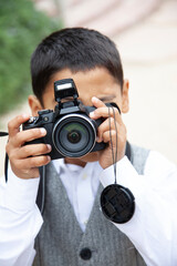 Fototapeta premium Little boy holding camera in front of face taking a picture of you