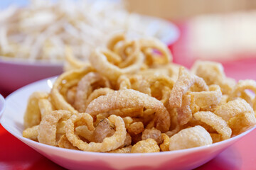 Pile of deep fried or bake pork snack, pork rind, pork scratching or pork crackling on white dish.