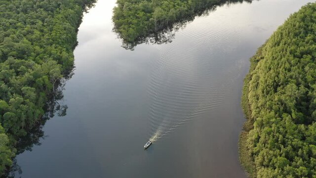 Vista a&eacute;rea do Rio Guaratuba com barco navegando, passando pela rodovia Rio Santos e encontrando com as  &aacute;guas do Mar