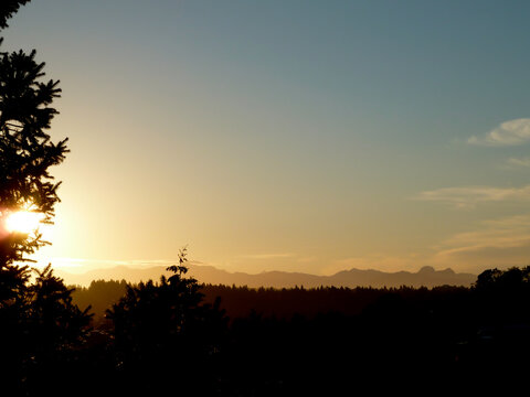 Bright sun and silhouette of the Northwest Cascades and evergreen forest of Washington State.