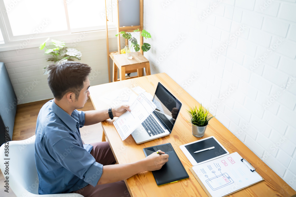 Fototapete Working from home web designing graphical user interface UX UI, home office using computer laptop and pen sketching graphics tablet device creative planning innovative ideas, asian man quarantine
