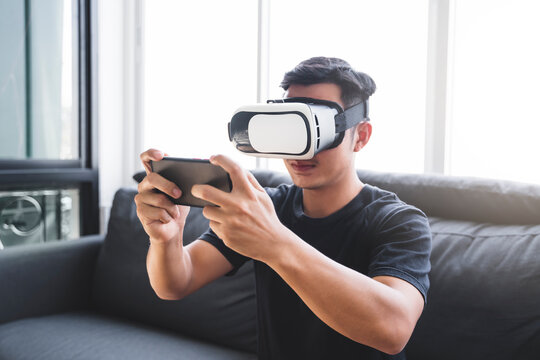 Virtual reality VR headset experience simulation, Asian man interacting in augmented reality playing games having fun using mobile smart device, futuristic technology, home quarantine self isolation