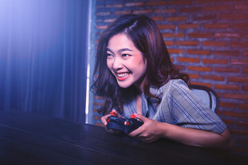 Asian Gamer girl woman nerdy geek casual playing video games computer using joy stick controller having fun excitement at home computer desk setup technology voice chat team play online cyberspace © Have a nice day 