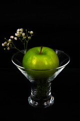 art photo green apple and white flowers in a glass on a black background