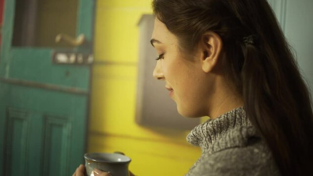 Young Female Sips Hot Coffee Against Colorful Painting, Medium