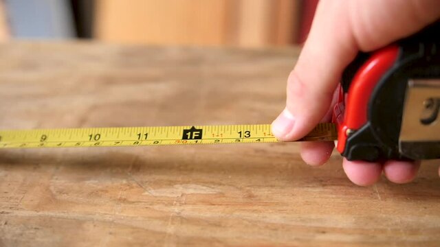 Slow motion pulling a tape measure across a piece of plywood and having it run through someone's hands.
