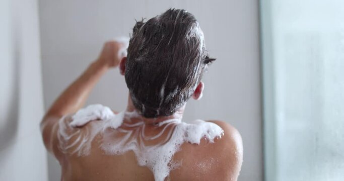 Man taking a shower washing back with body wash soap product under water falling from luxury rain shower head. Morning routine luxury home lifestyle guy showering. body care hygiene.