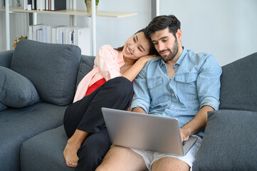 Happy and relax  lifestyle of young couple lover wearing casual dress together working on sofa with  laptop notebook computer in living room at home.