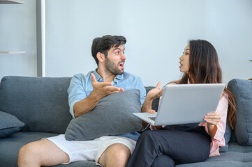 Fototapeta na wymiar Unhappy of young couple lover wearing casual dress together working on sofa with laptop notebook computer in living room at home.