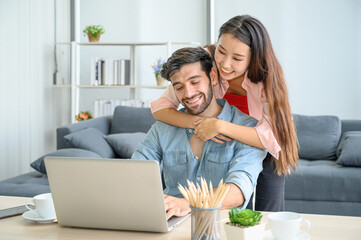 Happy and relax  lifestyle of young couple lover wearing casual dress together working on laptop notebook computer in living room at home.