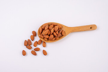 Almonds on wooden spoon isolated over white background. Top view