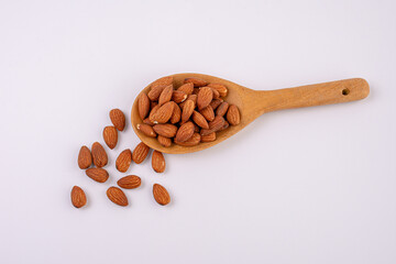 almonds and wooden spoon on white background 