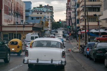 Naklejka premium Nostalgic retro and modern imported cars clash in downtown Havana, Cuba.