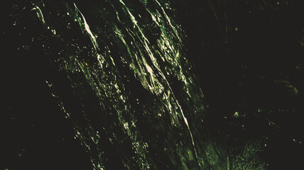 The waterfall flows, at night in a green light. Photo with post-processing.