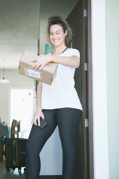 Beautiful caucasian young woman smiling receiving mail delivery package at home during covid 19 pandemic. 