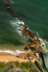 sea and rocky prominence in portugal where rocks make a natural extension from the sandy beach into the sea