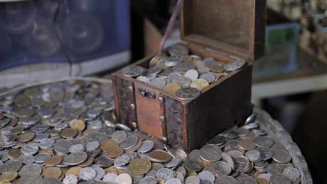 Opening the treasure box full of coins on pile of antique money