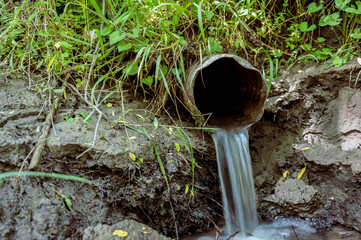 Water flowing from the open outlet of a metal agriculture drainage tile