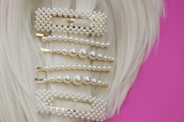 pearl hair clips on blond hair close-up. fashionable hair accessories. Hairpin with pearls on a...