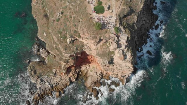 A crowd of tourists gathered by the edge of a mountain cliff in Bulgaria to enjoy the view - top view