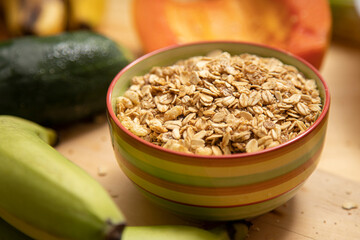 granola in a colorful bowl with fruits and vegetables around, selective focus