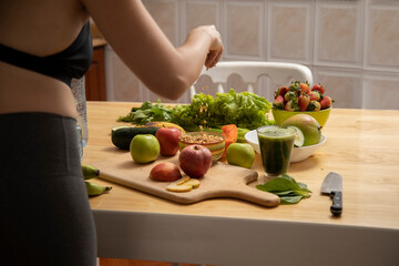 girl preparing green juice breakfast with fruits and vegetables