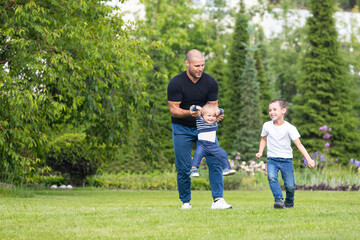 Obraz premium Cute cheerful two boys brother child with father play outdoors in park. Happiness and harmony of family life. Great family vacation.