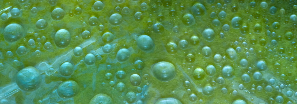 White-green and translucent green spheres of different diameters are located on a malachite-green background. Cosmic abstraction.