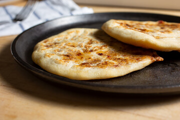 A view of pupusas on a comal, in a restaurant or kitchen setting.