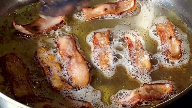 Close-Up Of A Slices Of Bacon Being Flipped On Stovetop.