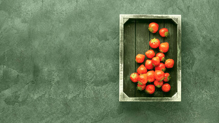 Fresh organic strawberry in vintage wooden box on green stone table. Healthy summer raw food concept.